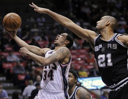 Novamente destaque do Spurs, Tim Duncan tenta parar Devin Harris (Foto por AP Photo)